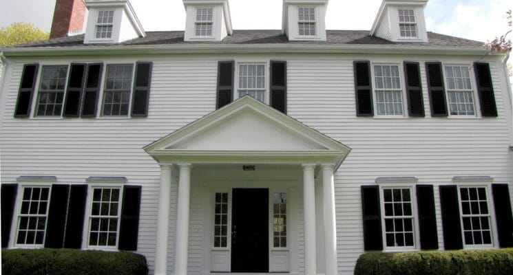 front exterior of the house with white siding and black shutters